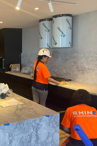 Rhino workers cleaning and preparing a kitchen countertop in an indoor setting.