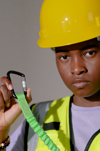 Rhino Construction worker holding a safety harness and wearing a yellow hard hat.