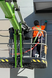 Rhino worker cleaning windows using a lift at an outdoor location.