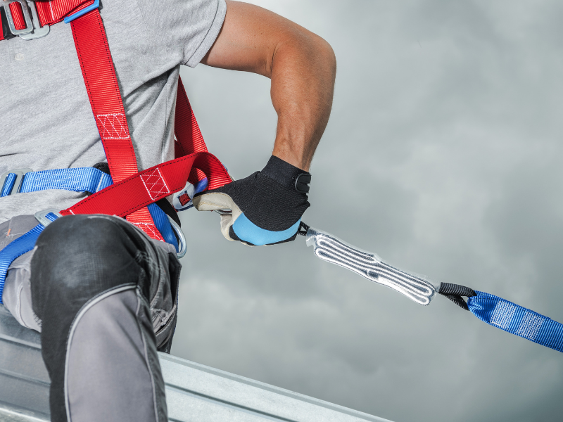 Worker in harness attaching safety line on a rooftop, Australia. Rhino Construction Services, concrete sealing.